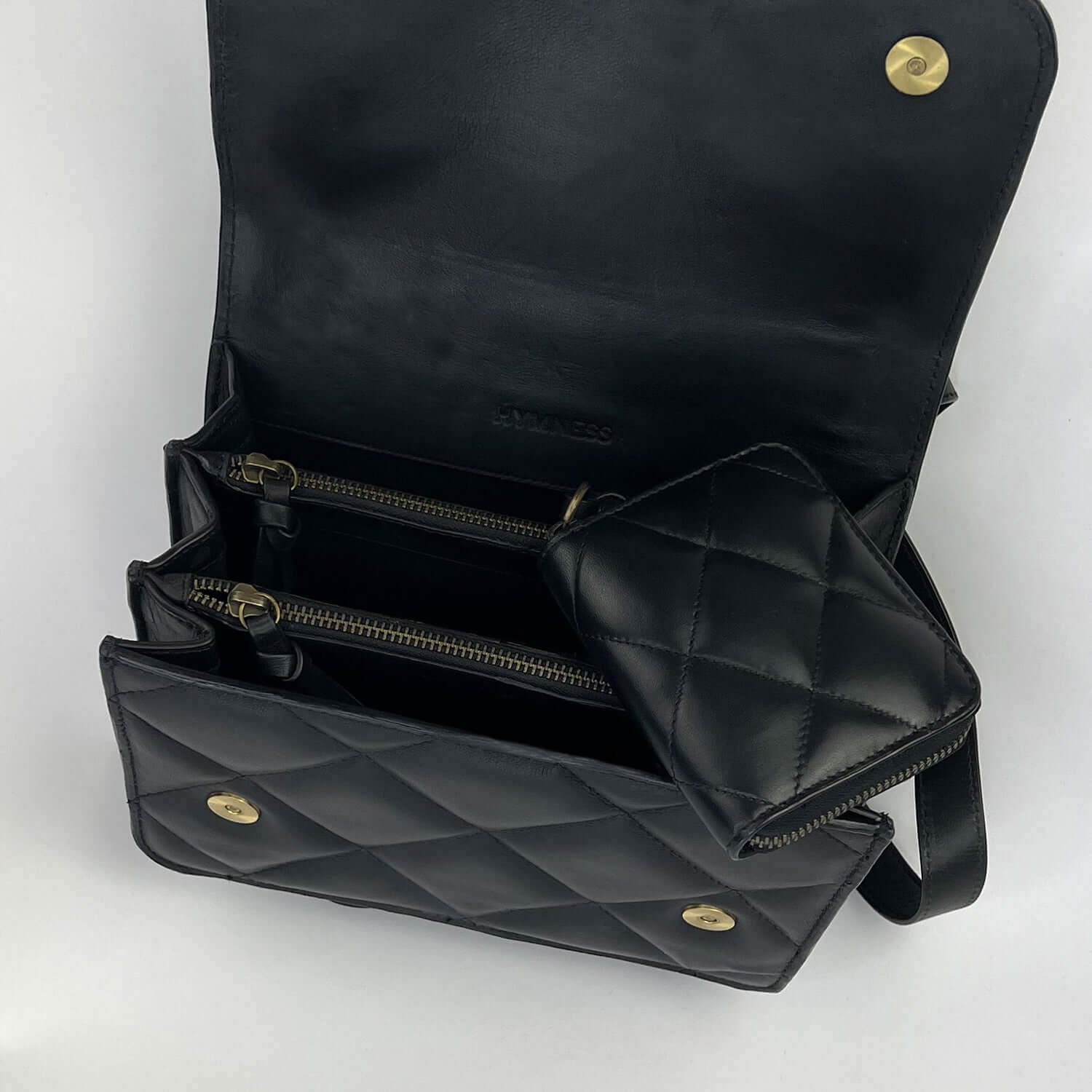 Black compartment bag with open flap, showing the inside of the bag with three open compartments and two zipped pockets.